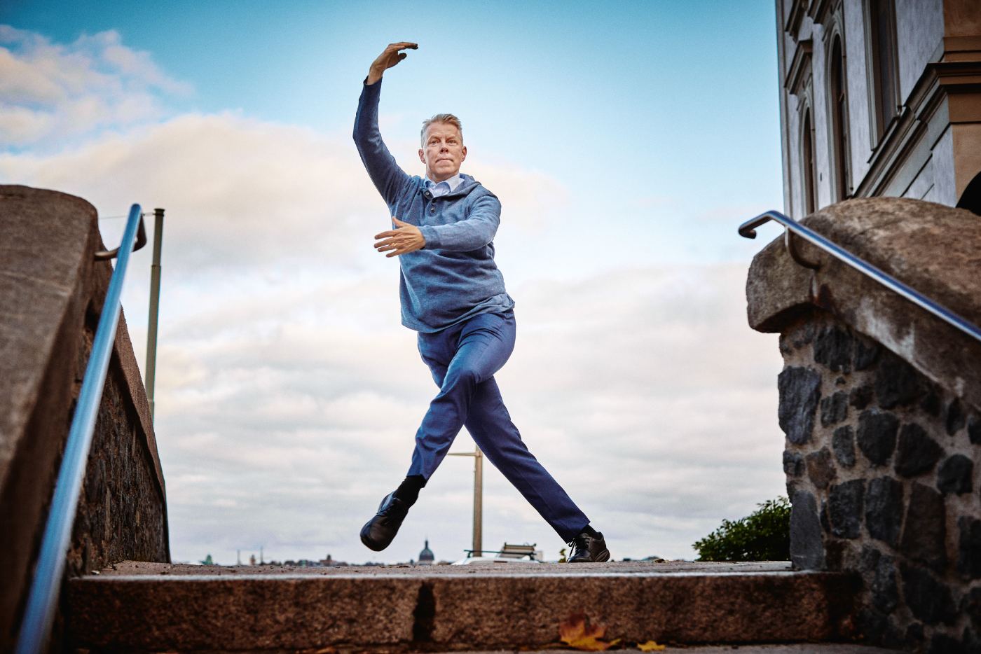 Jonny Boström i en dansposition på en trappa med Stockholms silhuett bakom